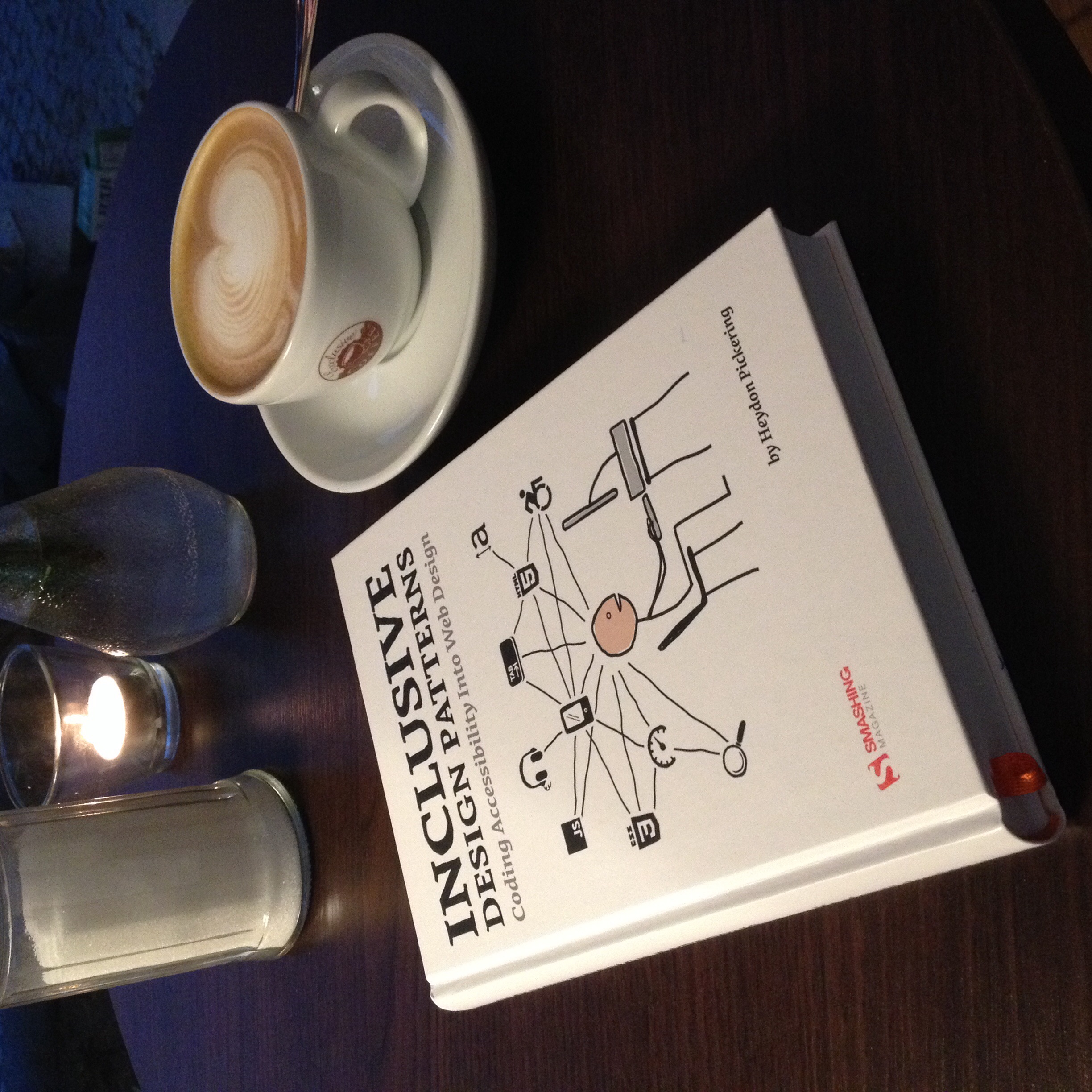 Buch „Inclusive Design Patterns“ auf Tisch neben Cappuccino