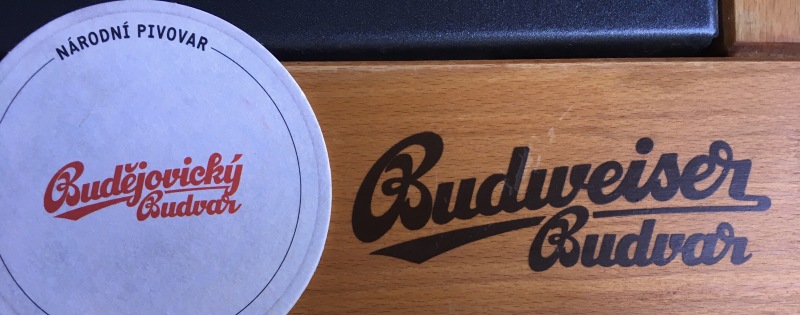 Bierdeckel mit Aufschrift „Budějovický Budvar“ auf Tisch mit Aufschrift „Budweiser Budvar“