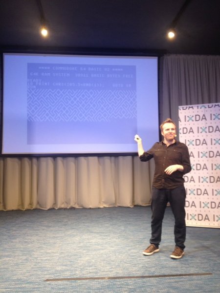 Seb Lee-Delisle beim IxDA Berlin, im Hintergrund der Screenshot eines BASIC-Programms auf dem C64